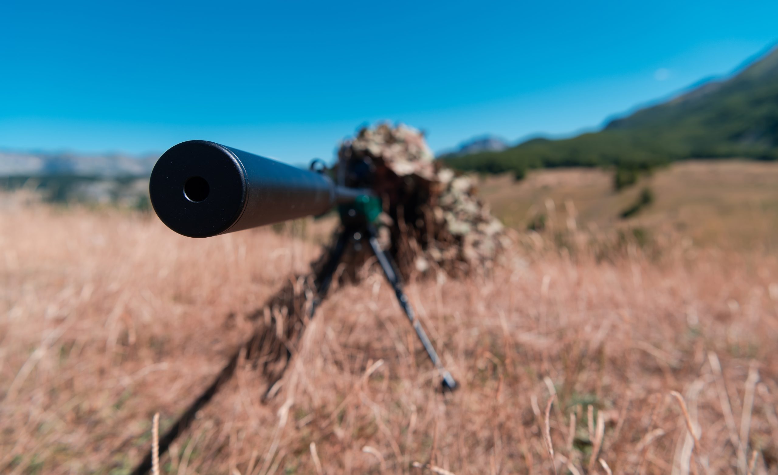 army soldier holding sniper rifle with scope and aiming in forest. war, army, technology and people concept